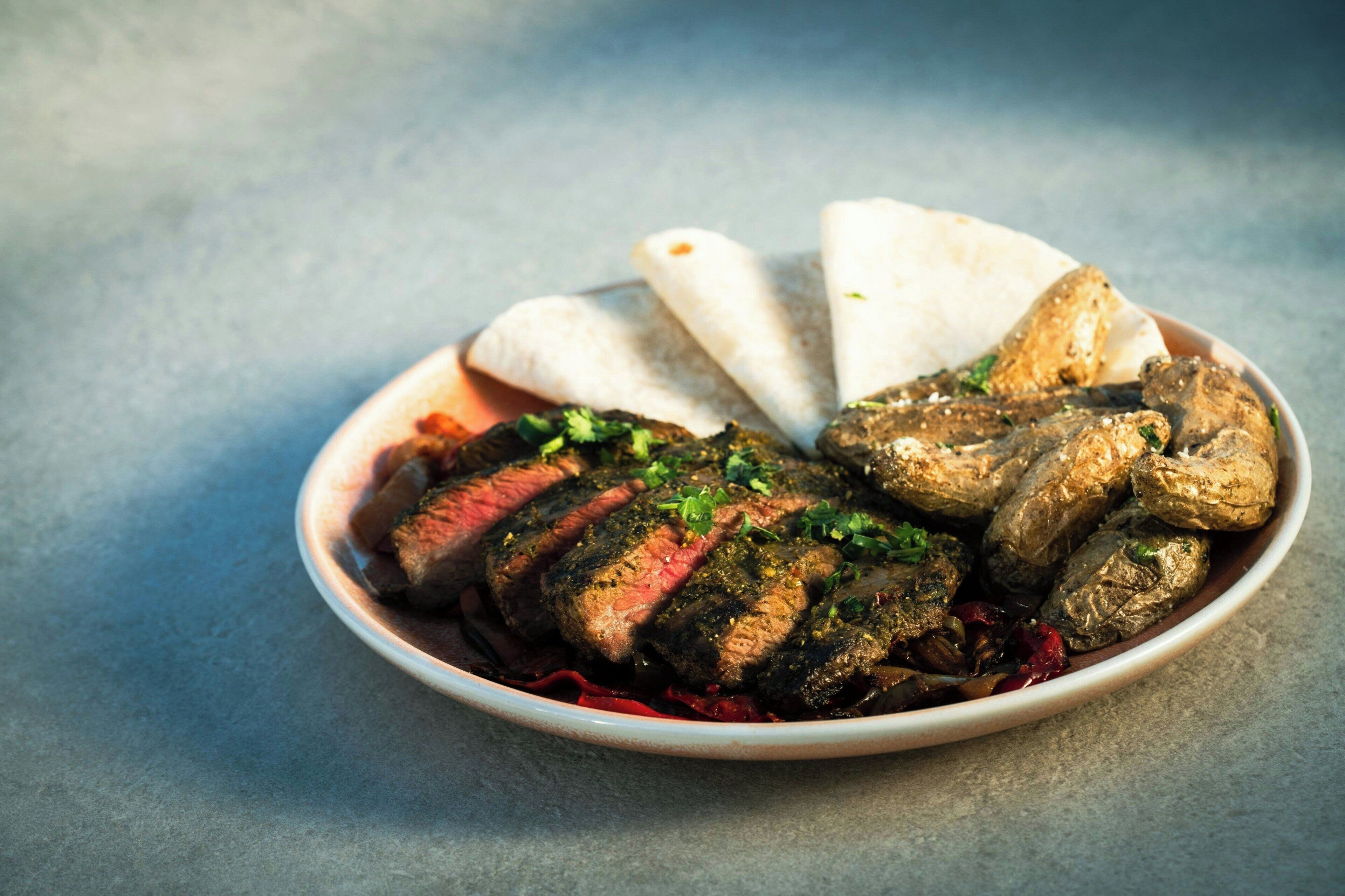 A plate with sliced meat, stuffed vegetables, and flatbread.