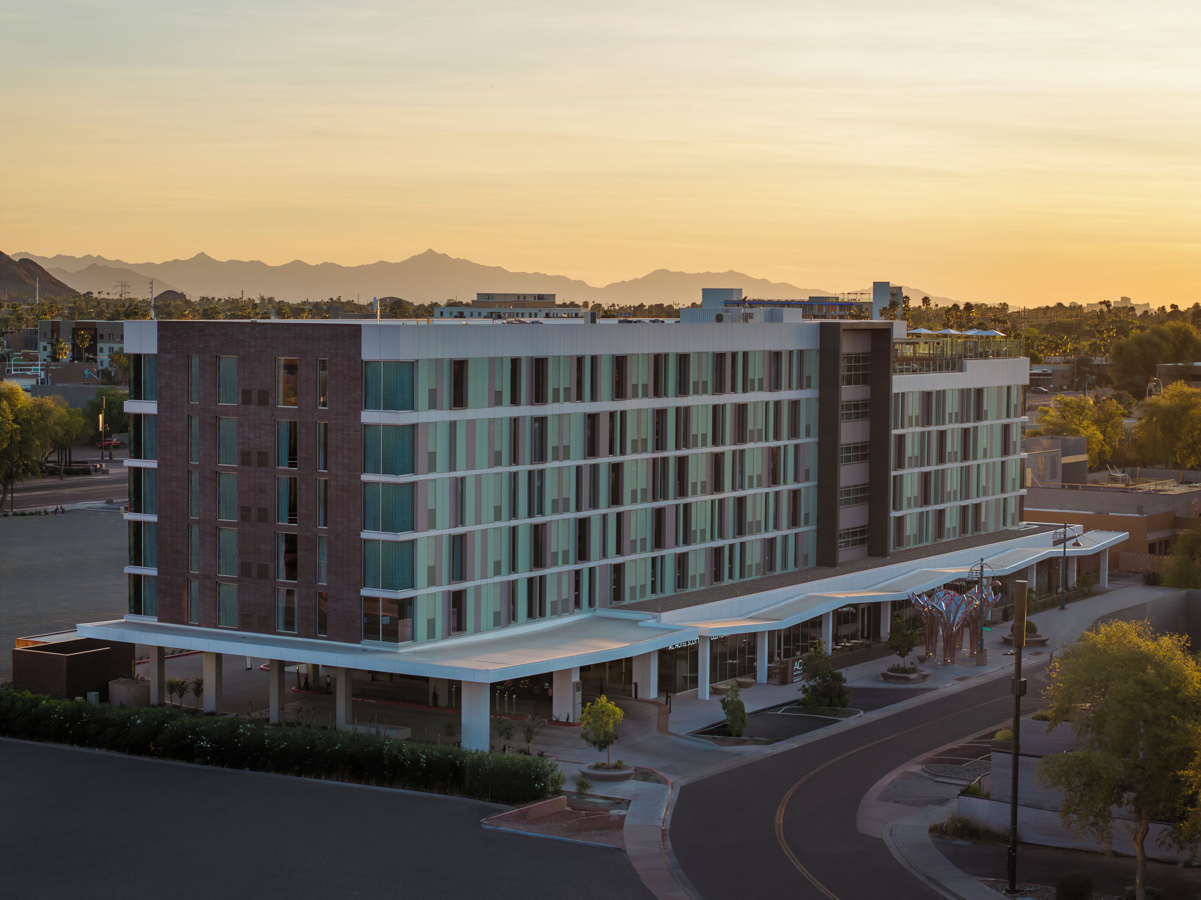 A modern multi-story building with a flat roof, large windows, and a covered entrance area.