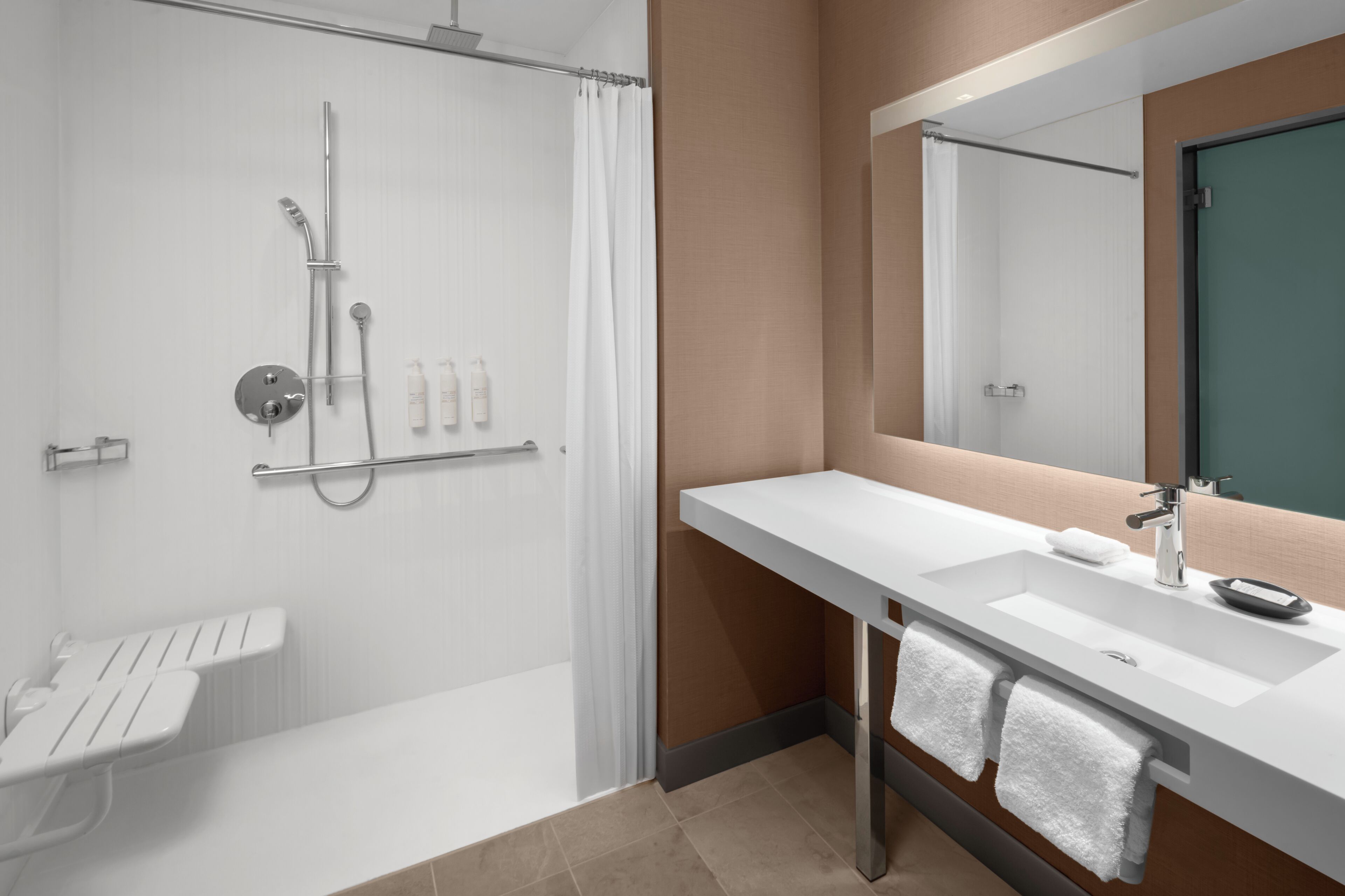 A modern bathroom with a shower, a sink, a mirror, and a towel rack.