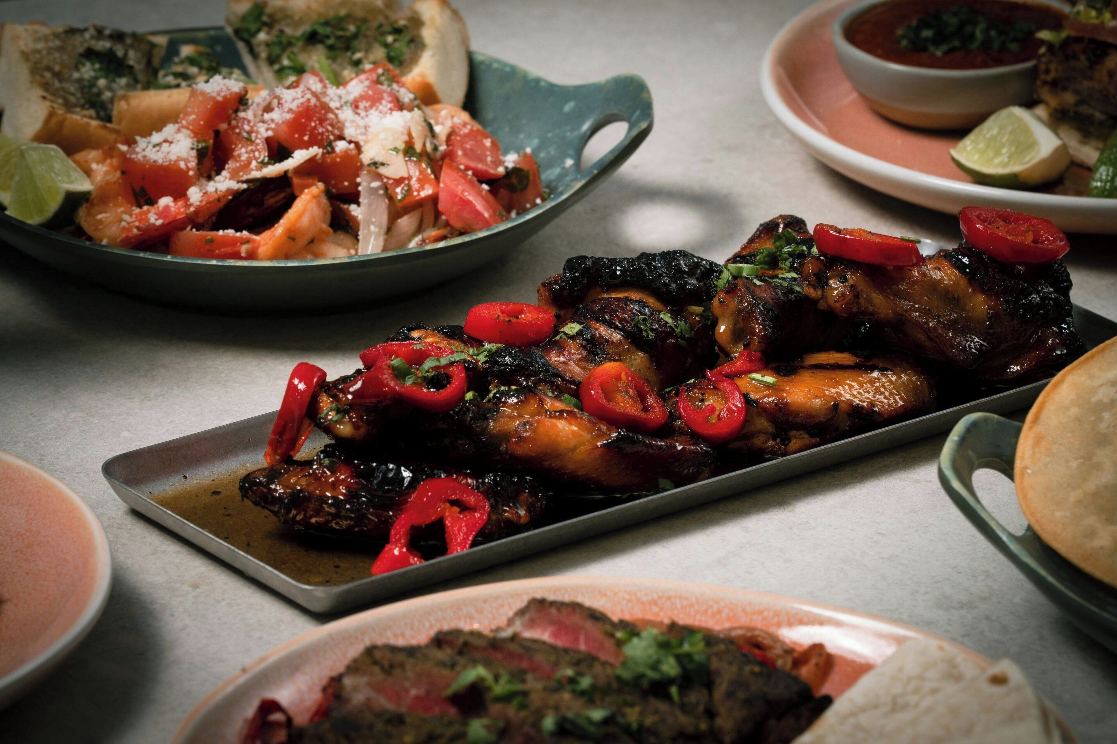A variety of dishes including grilled meat, vegetables, and bread, suggesting a dining setting.
