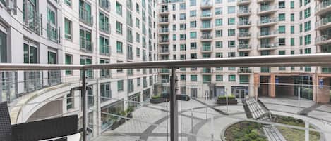 A modern building with multiple balconies and a circular courtyard with a central sculpture.