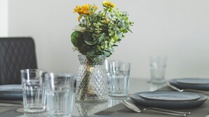 A dining table set with plates, glasses, and a vase with flowers. - Deluxe Two-Bedroom Vauxhall Apartment (London)