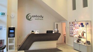 A reception area with a reception desk, a clock, a digital display, and a display case with products. - Deluxe Two-Bedroom Vauxhall Apartment (London)