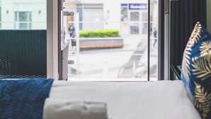 A hotel room with a bed, a window with a view of a building, and a curtain. - Deluxe Two-Bedroom Vauxhall Apartment (London)