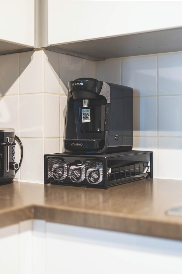 A coffee maker on a kitchen counter with a QR code and a Tassimo pod holder. - Deluxe Two-Bedroom Vauxhall Apartment (London)