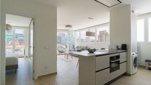 A modern kitchen with a central island, built-in oven, and a washing machine. - 3BR Ocean Sunset Suite Las Canteras (Las Palmas de Gran Canaria)