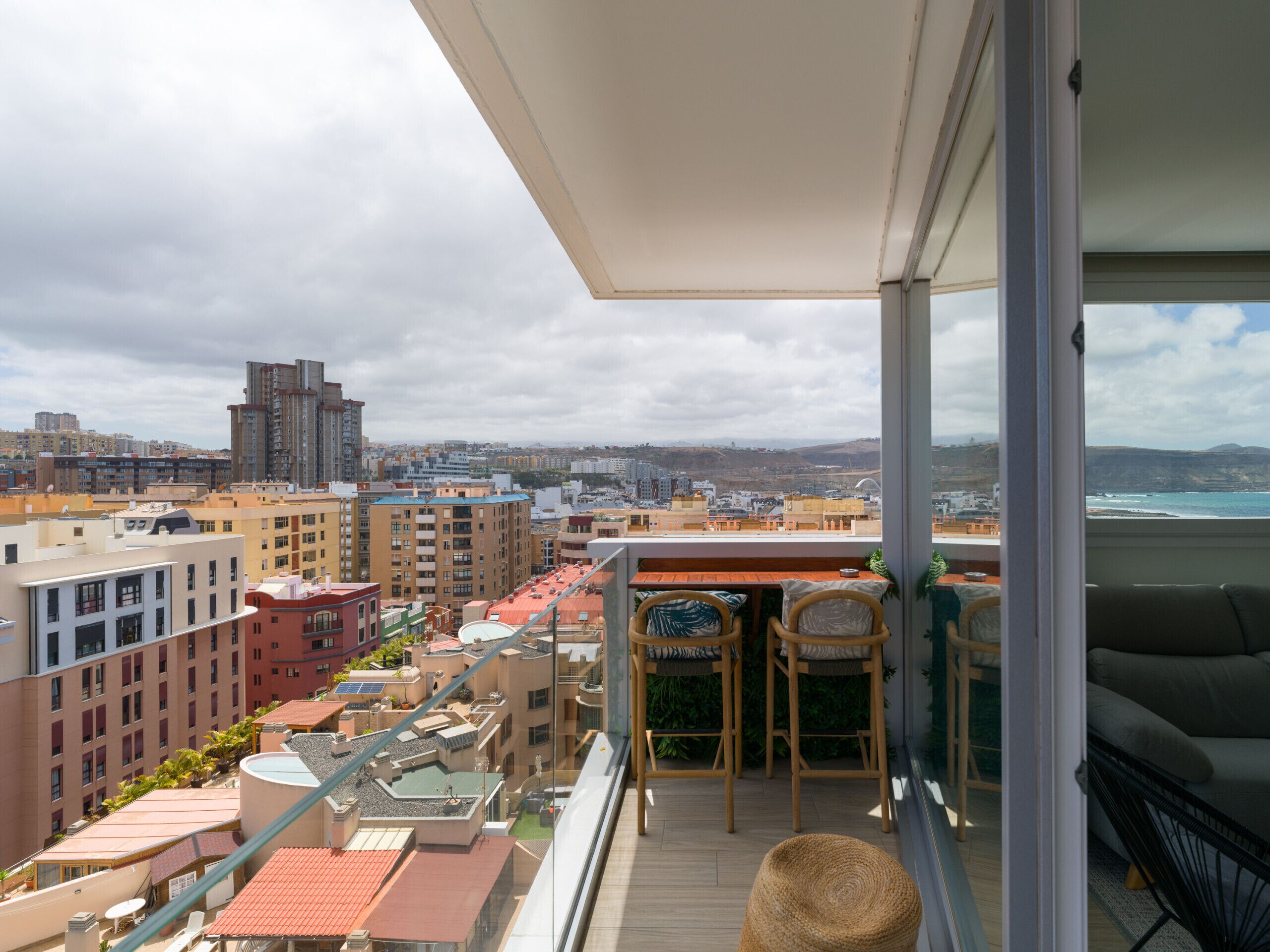 A balcony with a view of a cityscape and the sea.