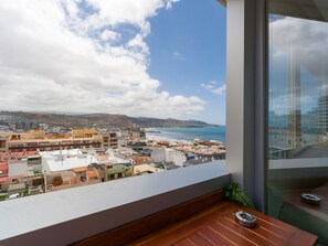 Ein Balkon mit Blick auf eine Küstenstadt, darunter Gebäude und das Meer.