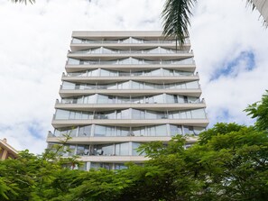 Ein mehrstöckiges Gebäude mit modernem architektonischen Design, das Balkone und große Fenster aufweist.