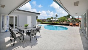 A covered patio with a pool, outdoor furniture, and a view of neighboring houses. - Intracoastal Villa | Pool + 40ft Dock | Sleeps 8 (Fort Lauderdale)