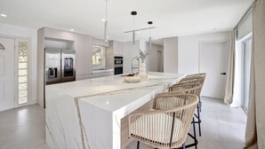 A modern kitchen with a marble island, built-in appliances, and a large window. - Intracoastal Villa | Pool + 40ft Dock | Sleeps 8 (Fort Lauderdale)