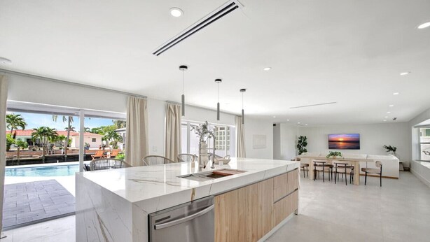 A modern kitchen with a large island, a dining area, and a view of a swimming pool. - Intracoastal Villa | Pool + 40ft Dock | Sleeps 8 (Fort Lauderdale)