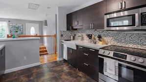 A modern kitchen with dark cabinets, a stainless steel microwave, and a gas stove. - Spacious 5-bedroom Tallahassee Home / Minutes to FSU & FAMU & The Capitol (Tallahassee)