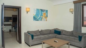 Ein modernes Wohnzimmer mit einem grauen Ecksofa, einem Holztisch und einem Gemälde an der Wand.