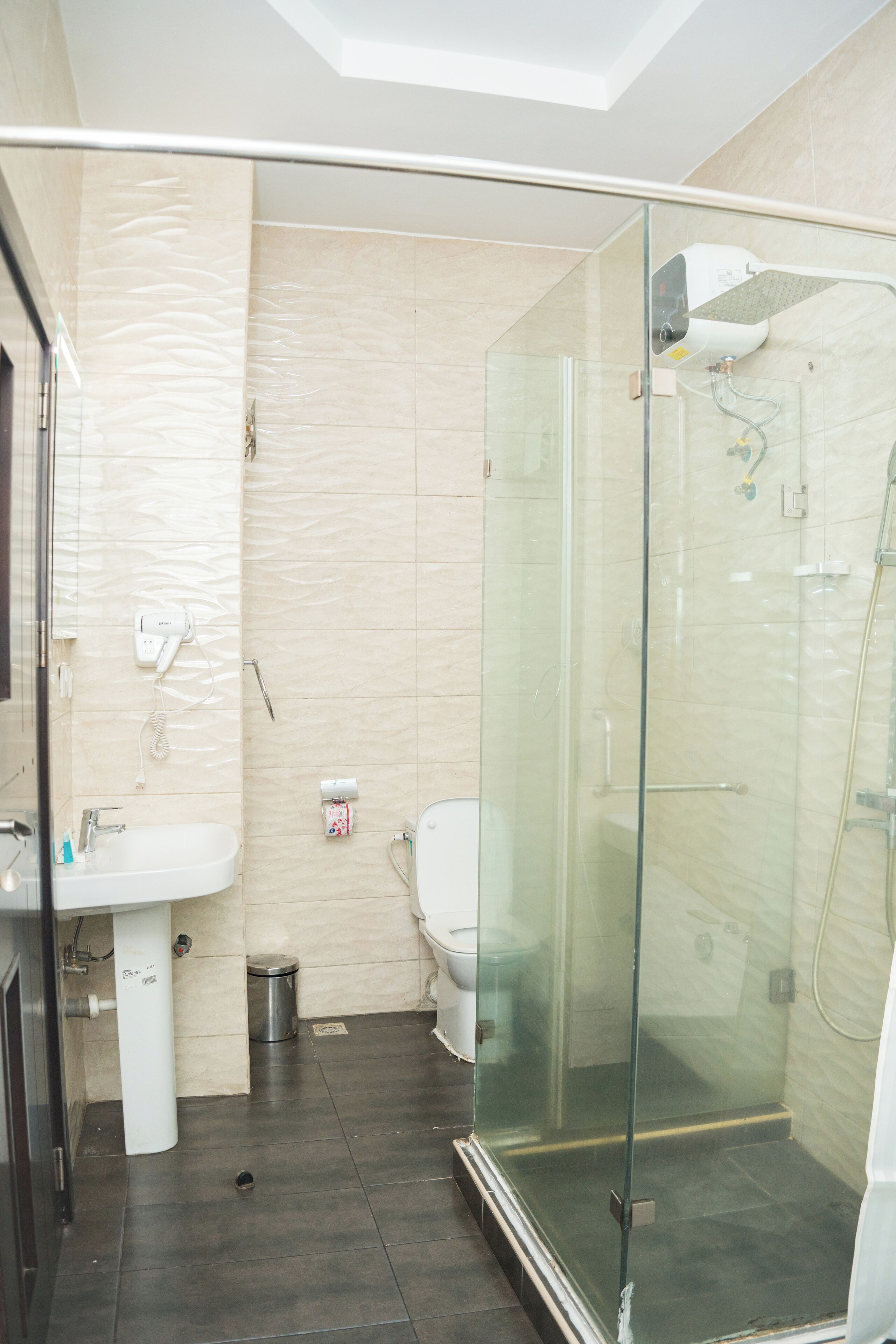 A modern bathroom with a glass-enclosed shower, a sink, and a toilet.