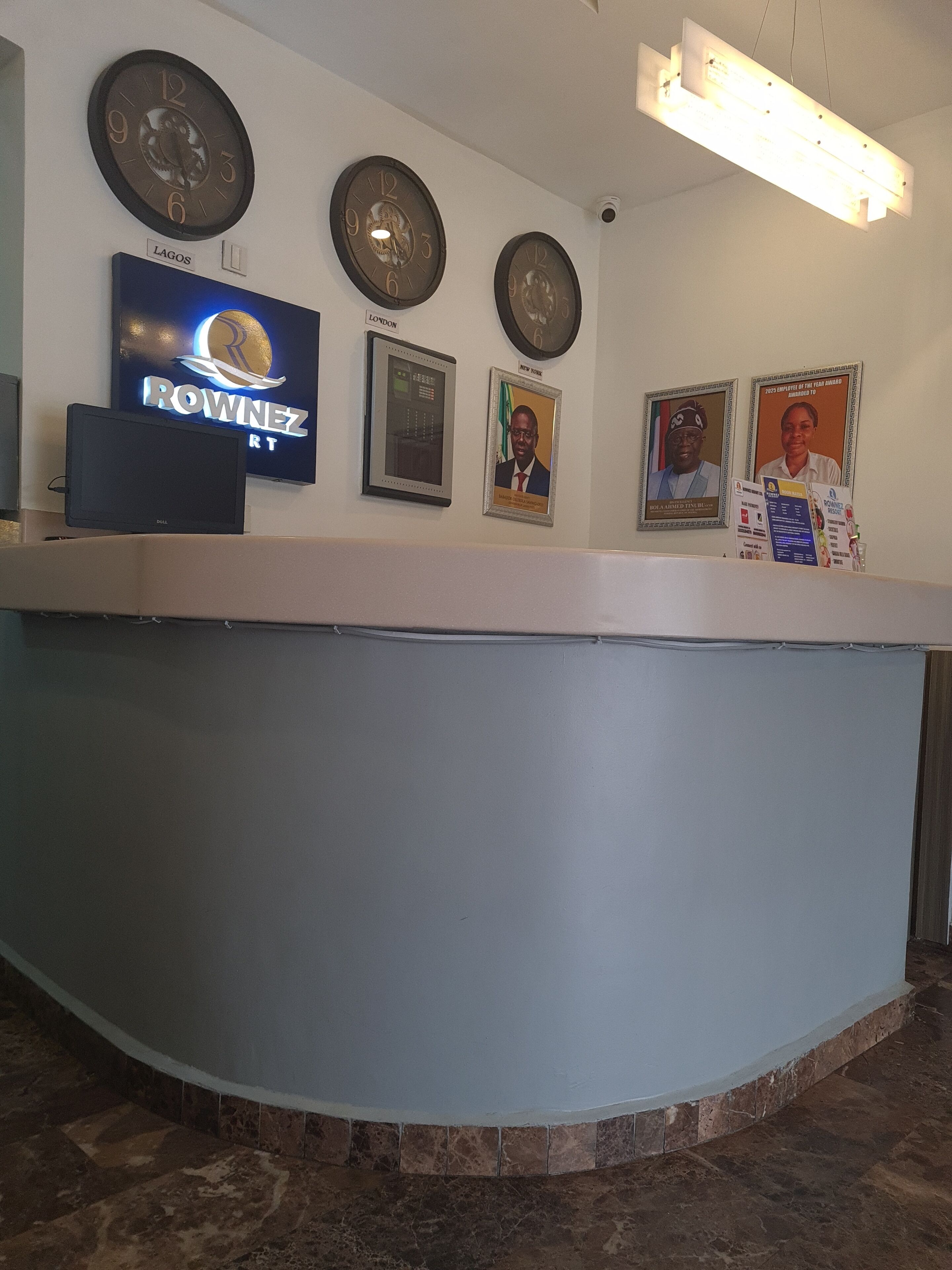 Un mostrador de recepción con un televisor de pantalla plana, tres relojes de pared y diplomas enmarcados.