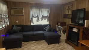 Ein Wohnzimmer mit einem Ecksofa, einem Fernseher, einem Kamin und einem Schachbrettmuster-Boden.