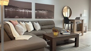 Un salón moderno con un sofá modular, una mesa de centro y dos grandes cuadros de paisajes.