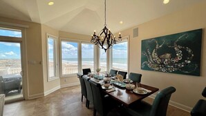 A dining area with a view of the beach, a chandelier, and a large painting. - Beach & Bay Views at Ocean Oasis in Brigantine! (Brigantine)