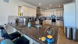 A modern kitchen with granite countertops, stainless steel appliances, and white cabinetry. - Beach & Bay Views at Ocean Oasis in Brigantine! (Brigantine)