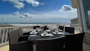 A balcony with a table set for dining, overlooking the ocean. - Beach & Bay Views at Ocean Oasis in Brigantine! (Brigantine)