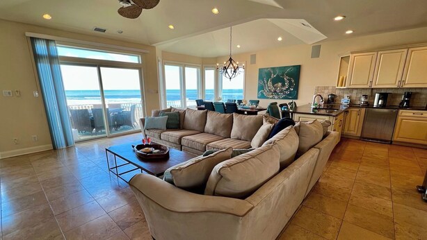 A spacious living room with a large beige sectional sofa, a dining area with a table and chairs, and a kitchen with modern appliances. - Beach & Bay Views at Ocean Oasis in Brigantine! (Brigantine)