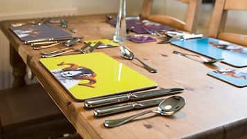 A wooden dining table with cutlery and placemats.