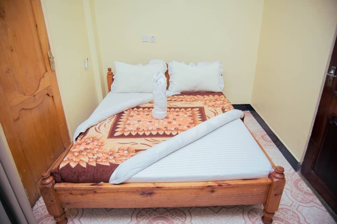 A single bed with a floral-patterned bedspread, two pillows, and a white blanket.