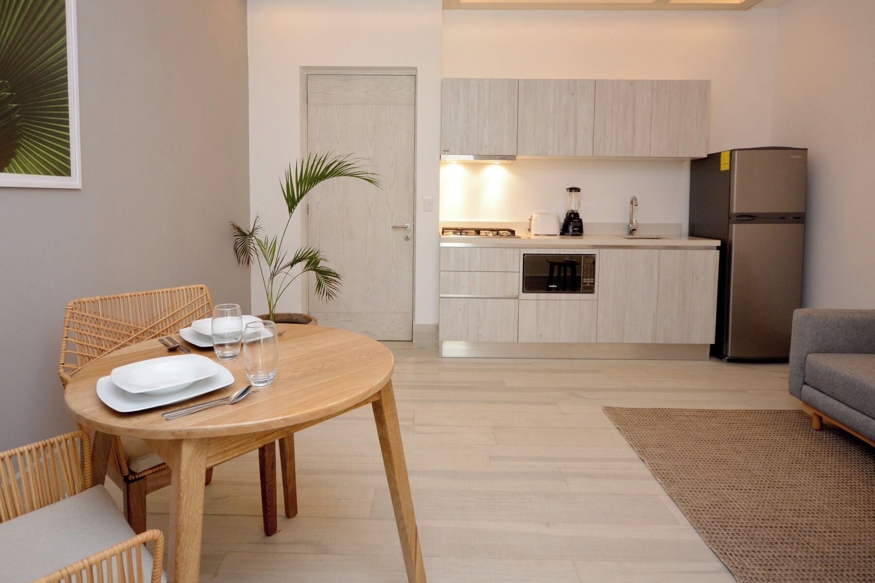 Een moderne keuken met lichte houten kastjes, een inbouwoven en een roestvrijstalen koelkast.