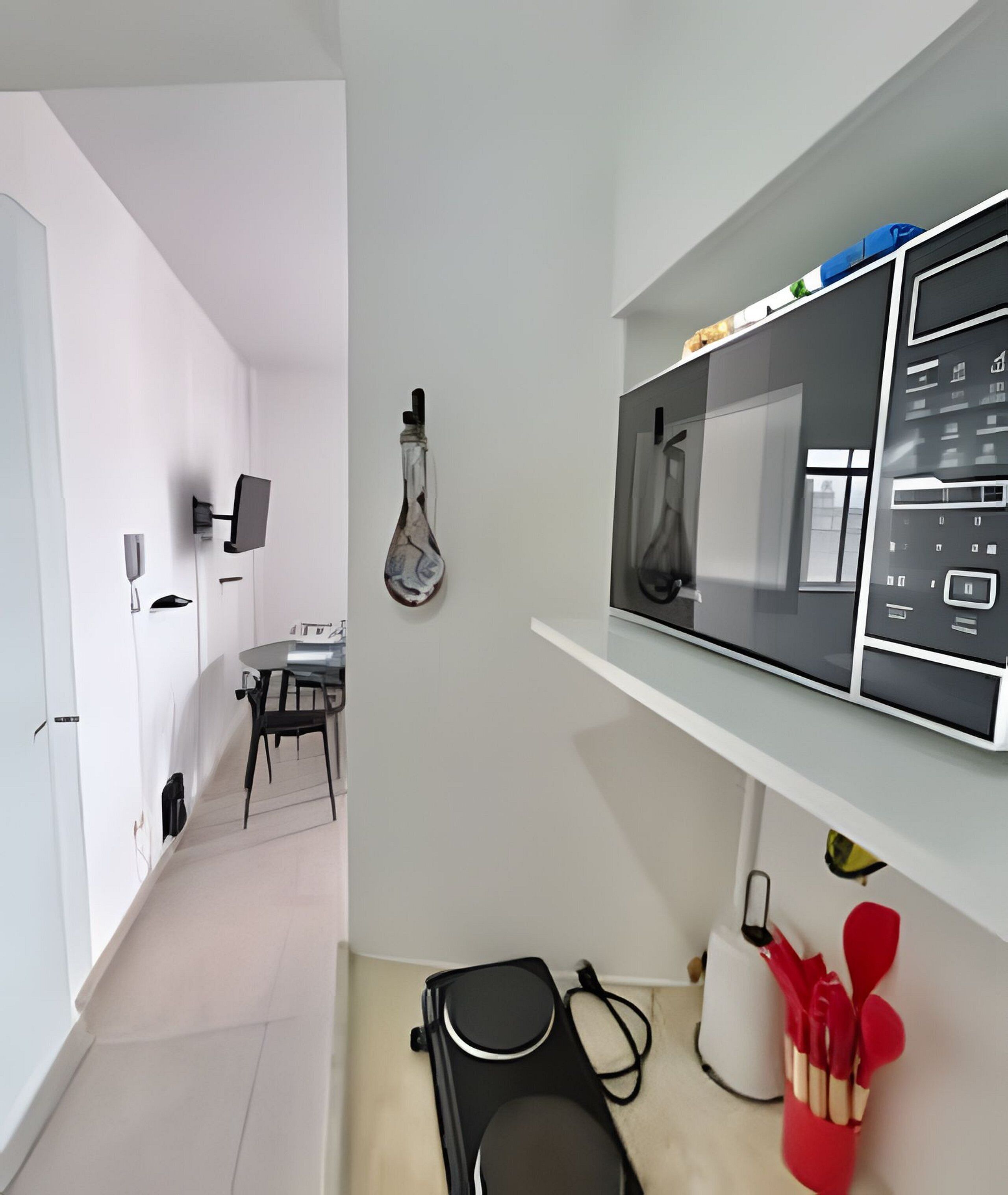Eine moderne Küche mit Essbereich, einem wandmontierten Fernseher und einem Regal mit Küchenutensilien.