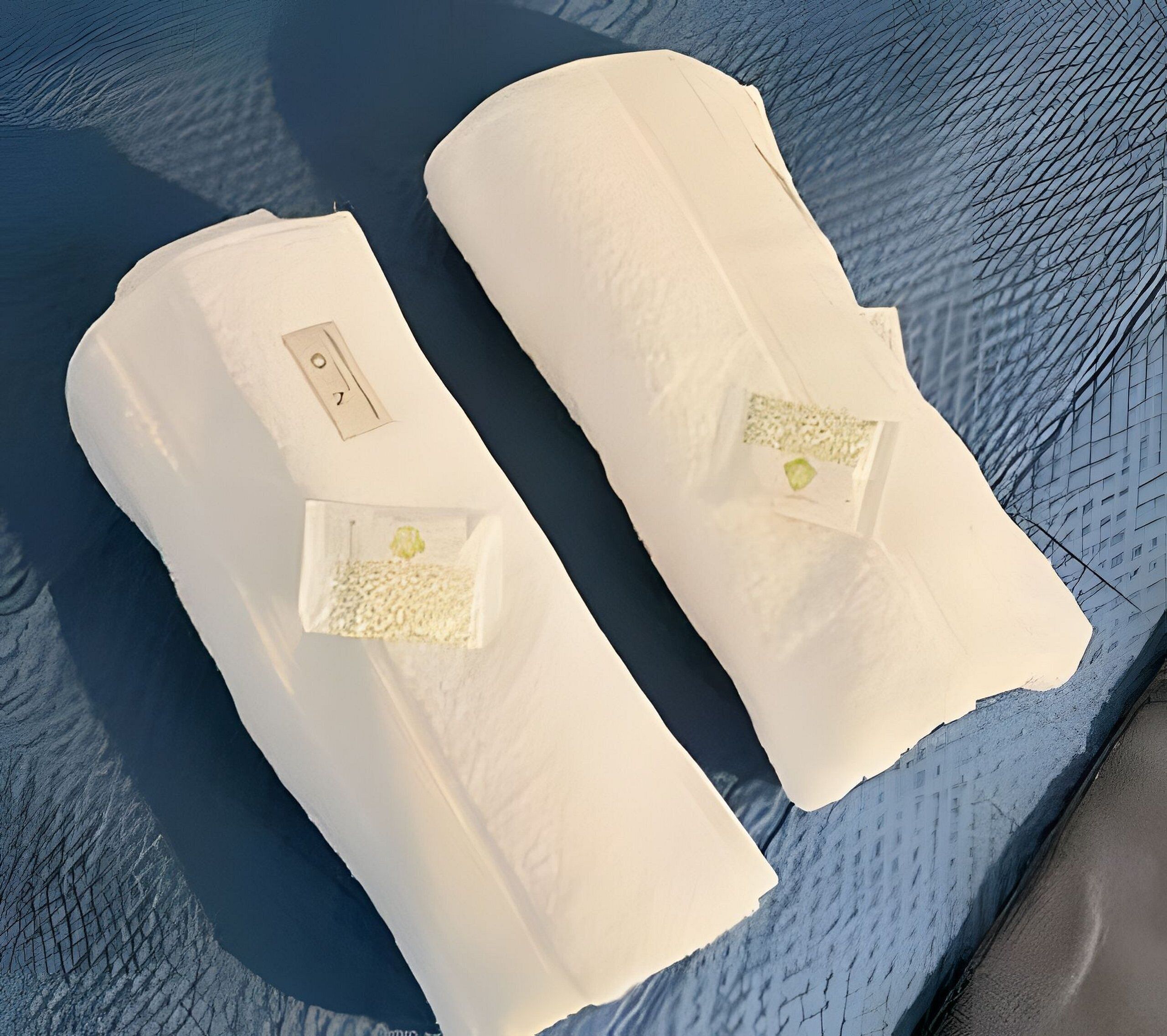Dos toallas blancas enrolladas con una pequeña etiqueta en cada una, sobre una superficie azul texturizada.