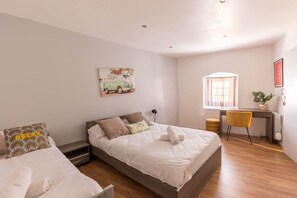 A bedroom with a bed, a desk, a chair, a window, and a wall art piece.