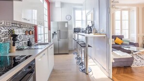 Una cocina moderna con refrigerador, microondas y taburetes de bar.