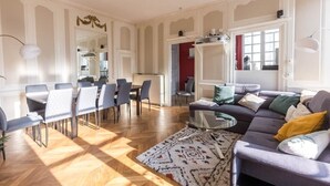 Amplia sala de estar con mesa de comedor, sillas, sofá y alfombra estampada.