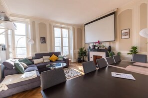 A modern living room with a sofa, a coffee table, a fireplace, and a large screen. - Villa Barillerie 1870 - Centre - 24 personnes (Le Mans)