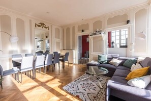 A spacious living area with a dining table, chairs, a sofa, and a patterned rug. - Villa Barillerie 1870 - Centre - 24 personnes (Le Mans)