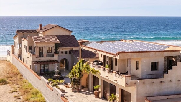 Een kustpand met een ruime woning, een balkon, een dak met zonnepanelen en uitzicht op zee.