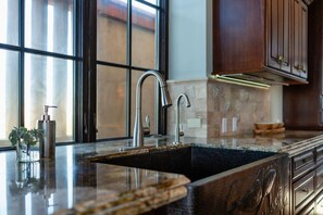 A kitchen with a stainless steel sink, a faucet, and a window with blinds.