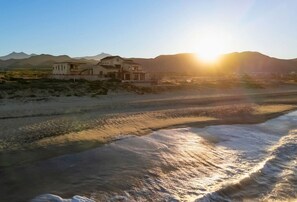 A coastal property with a beach, a house, and mountains in the background. - Château Cerritos | Luxe Oceanfront Home (La Paz)