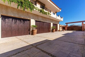 A building with a flat roof, large brown garage doors, and a balcony with greenery.