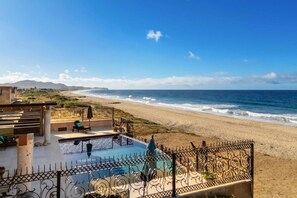 A pool area with a view of the beach and ocean.