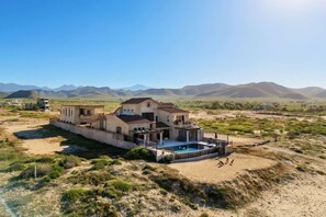 A large house with a swimming pool, surrounded by a desert landscape and mountains. - Château Cerritos | Luxe Oceanfront Estate (La Paz)
