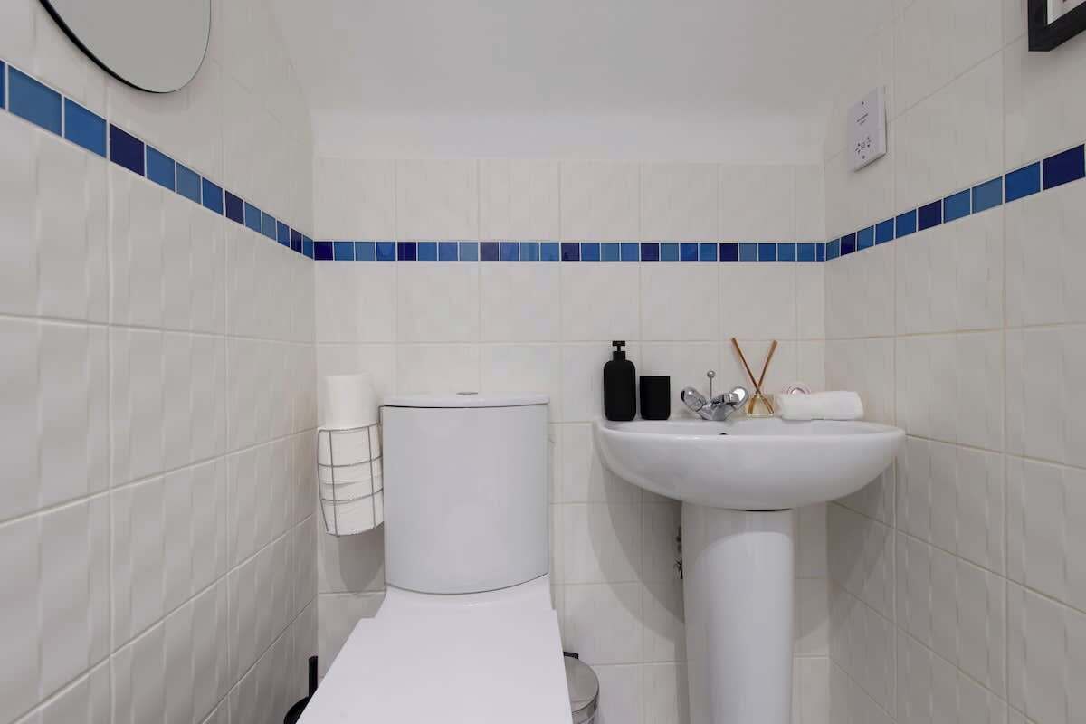 Une salle de bain avec des carreaux blancs, des toilettes, un lavabo et un miroir.
