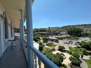 A balcony with a view of a cityscape, including a roundabout and a hill with buildings. - hotel europe meidan (Tbilisi)