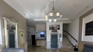 A spacious lobby with a reception desk, a staircase, and a seating area. - hotel europe meidan (Tbilisi)