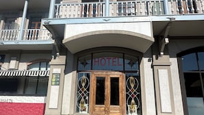A hotel entrance with a wooden double door, a balcony with railings, and a sign indicating the hotel's name. - hotel europe meidan (Tbilisi)