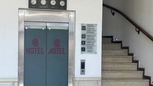 A hotel entrance with a double door elevator, a staircase, and a sign indicating hotel rooms and a restaurant. - hotel europe meidan (Tbilisi)