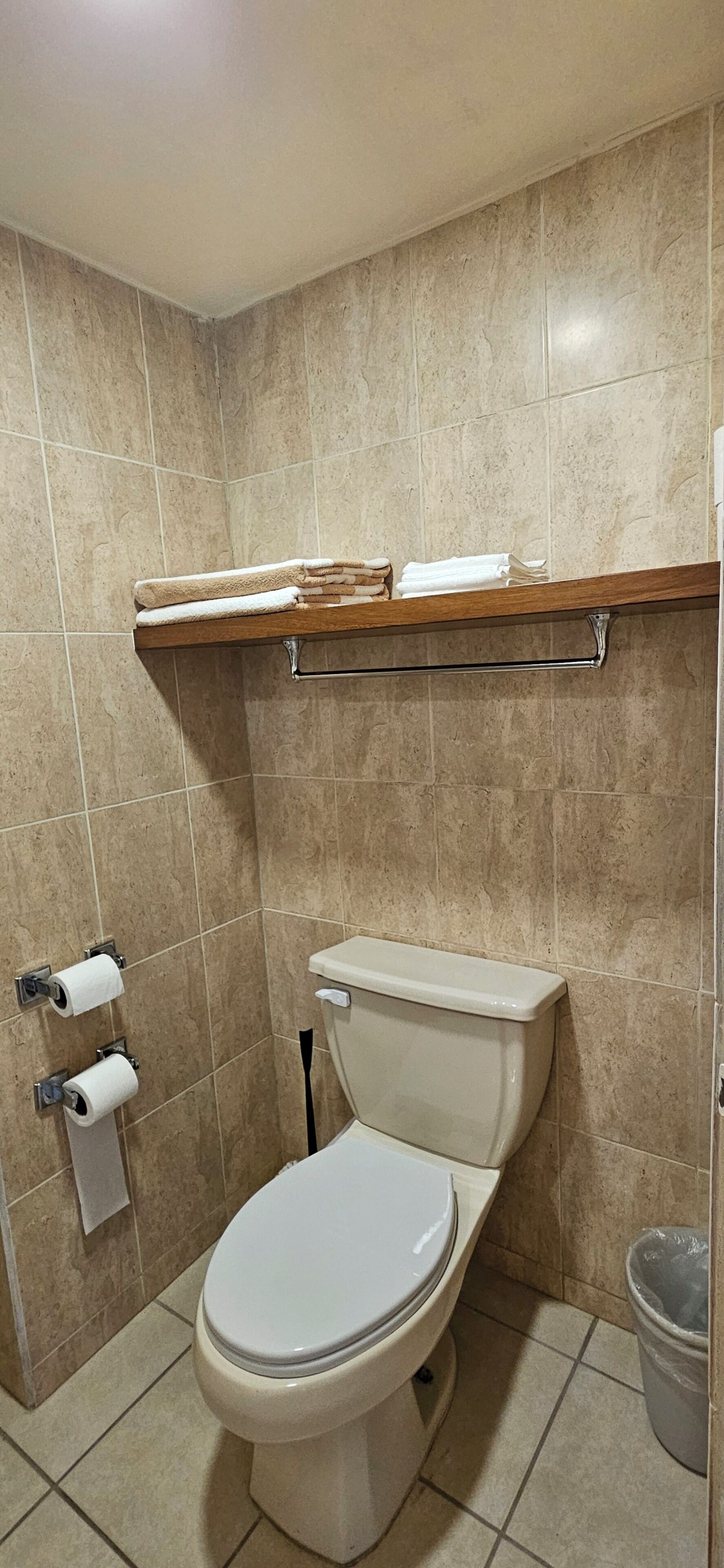 Une salle de bain équipée de toilettes, d’un porte-serviettes et de deux rouleaux de papier toilette.