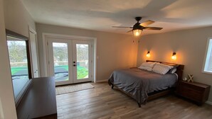 Ein Schlafzimmer mit einem Bett, einem Deckenventilator, einem Nachttisch und einem Fenster.