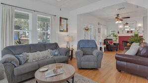 A spacious living room with a grey sofa, armchairs, a coffee table, and a fireplace.